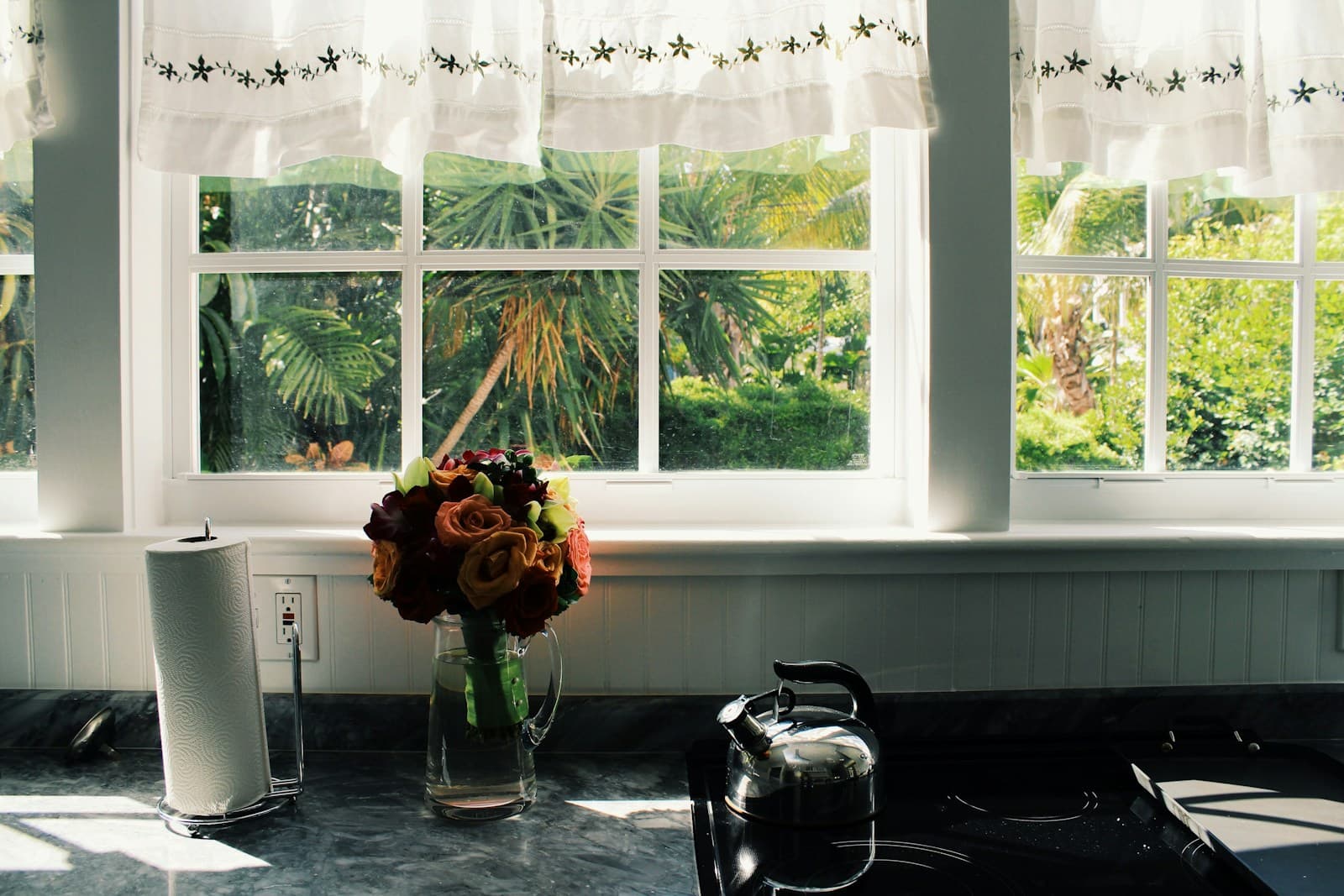 Bright sunlit kitchen counter with flowers by open windows