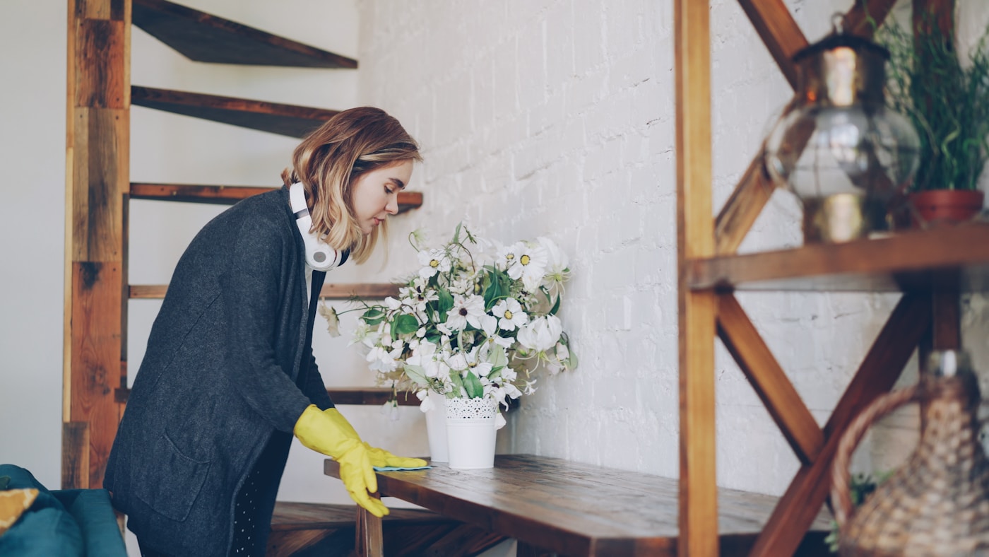 Cleaner in yellow gloves wiping a wooden table