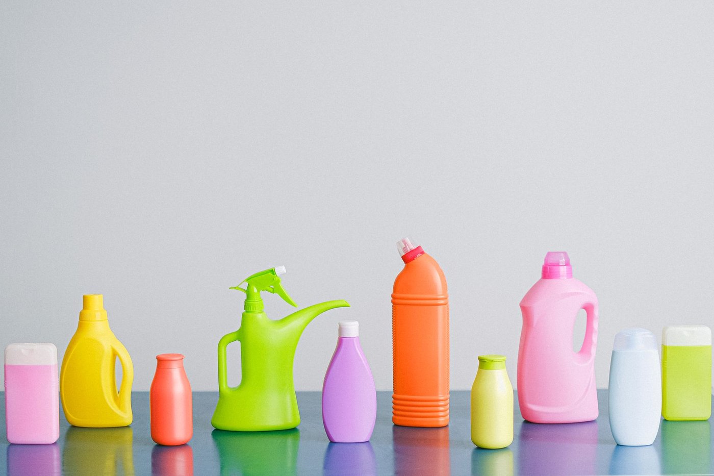 A row of assorted colorful household cleaning product bottles