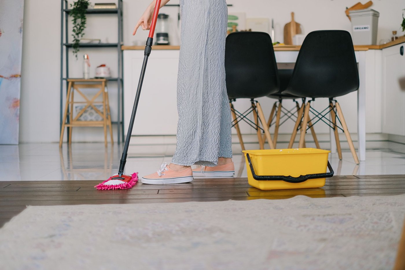 Mopping a hardwood floor with a flat mop and a cleaning bucket
